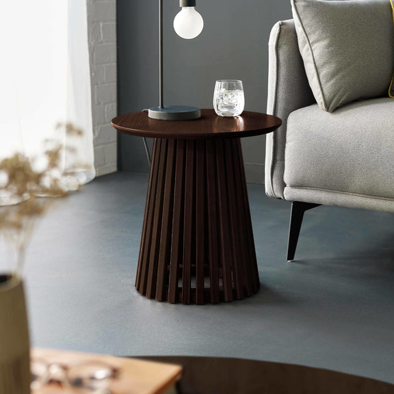 Wooden side table with a lamp and glass in a living room setting