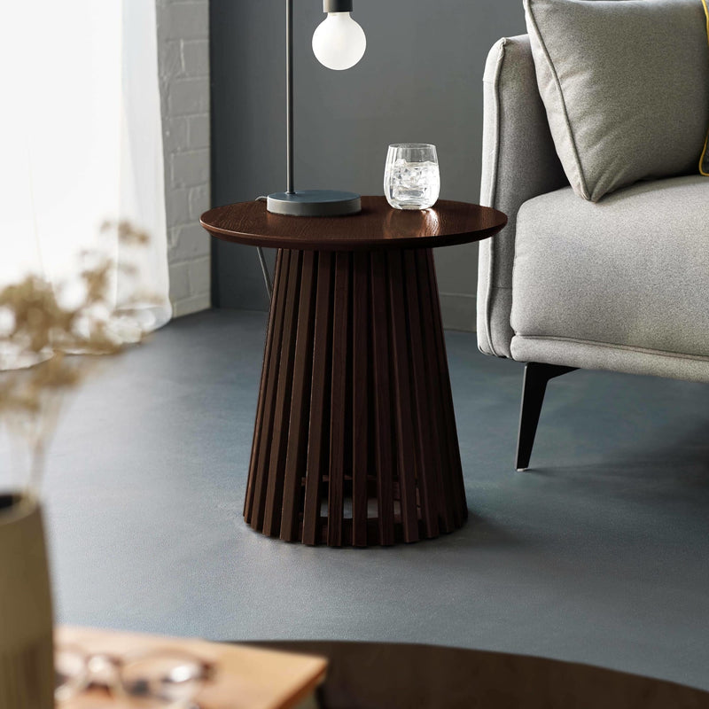 Wooden side table with a lamp and glass in a living room setting