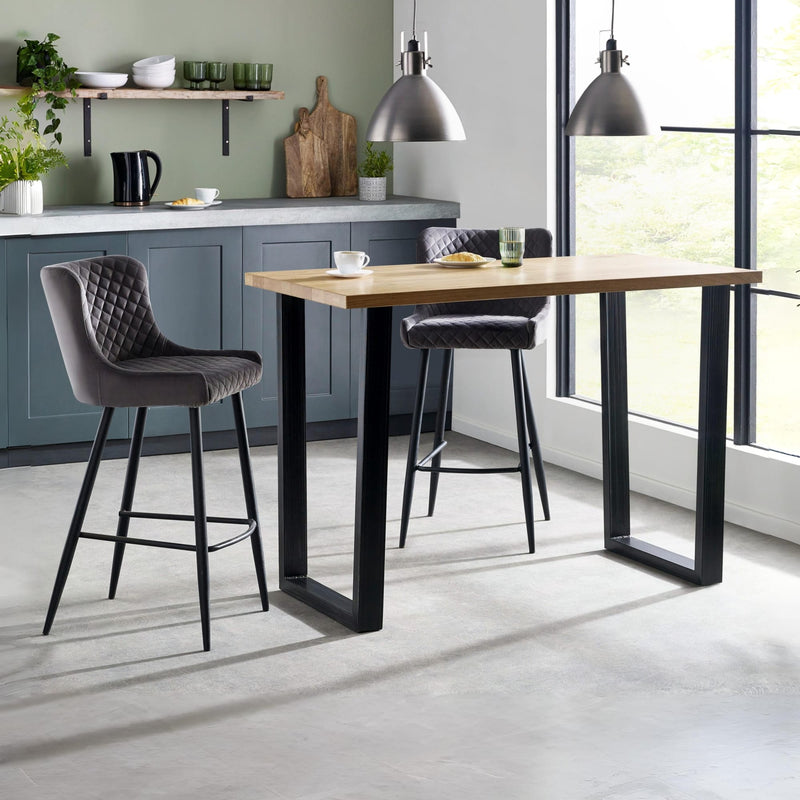 Modern kitchen with a wooden dining table and gray bar stools.