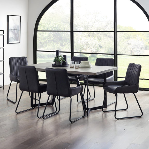 Dining room with a modern table and black chairs in front of large windows.