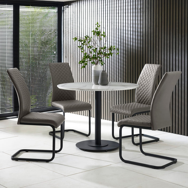 Modern dining set with four gray chairs and a round table in a room with large windows.