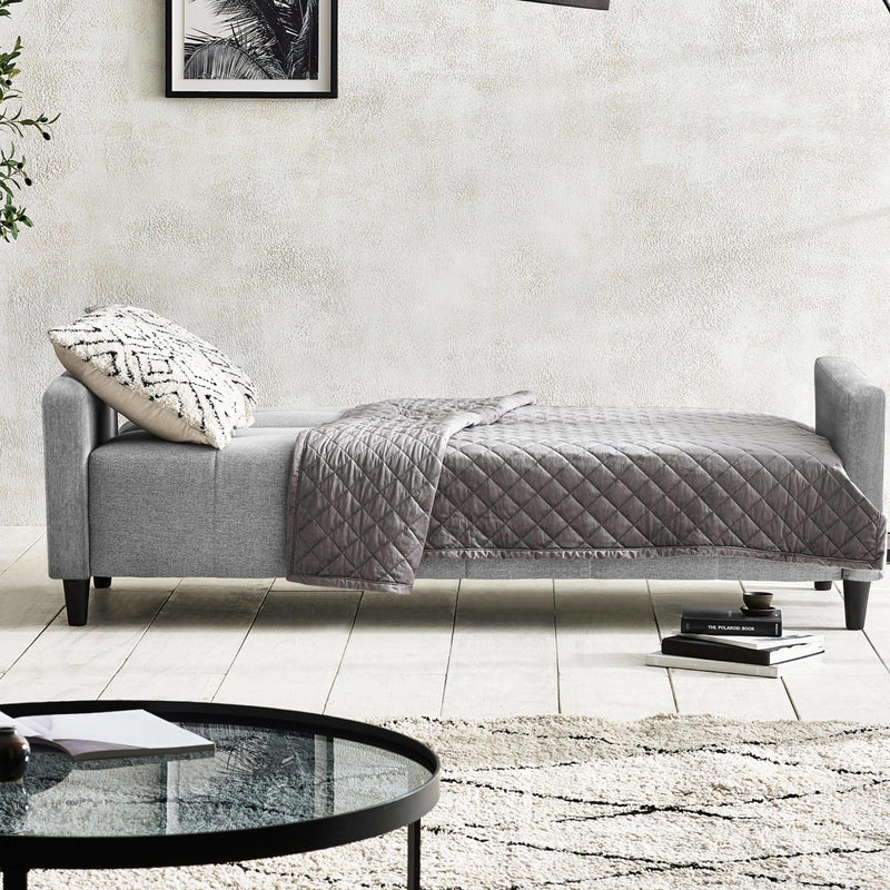 Gray sofa with a quilt and pillow in a modern living room setting.