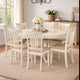 Dining room with a white table and chairs on a beige rug, decorated with flowers and a lamp.