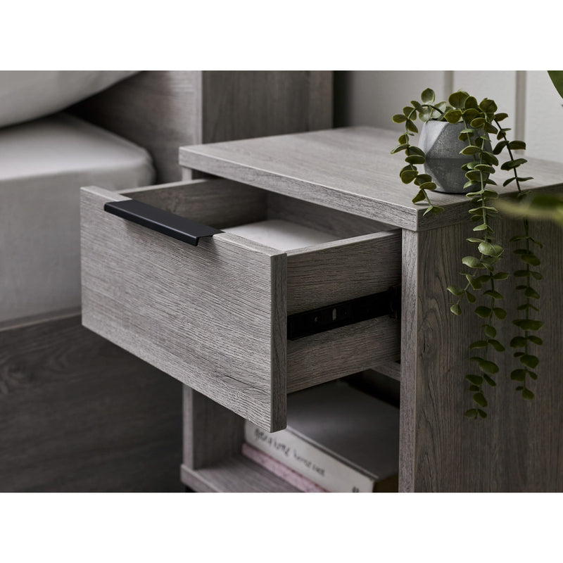 Wooden side table with open drawer, books, and a plant in a room setting.