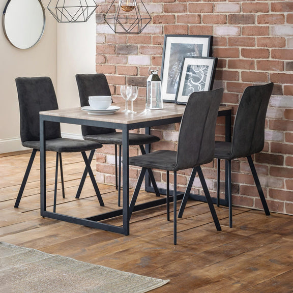 Dining area with a table and four chairs against a brick wall.