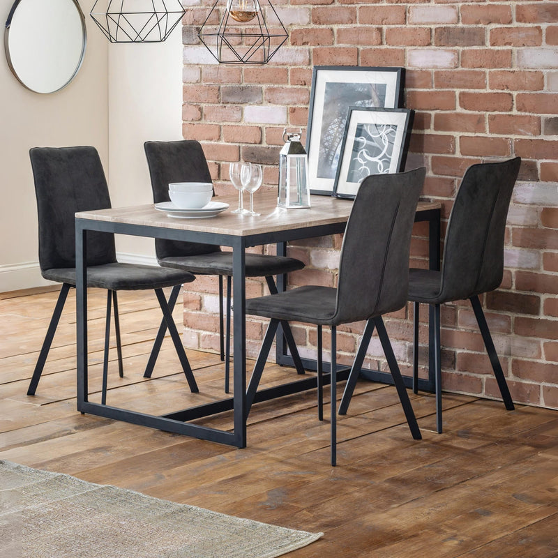 Dining area with a table and four chairs against a brick wall.
