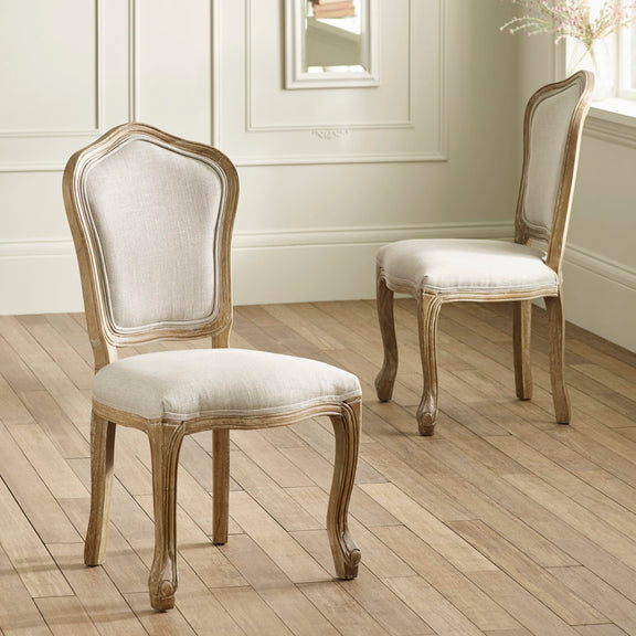 Two wooden chairs with upholstered seats on a wooden floor.