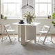 White dining table with chairs in a bright room with large windows.