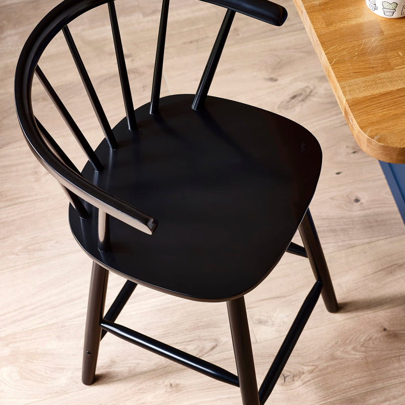 Black chair on a wooden floor with a wooden table in the background