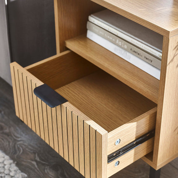 Wooden shelf with a drawer and books on a dark floor
