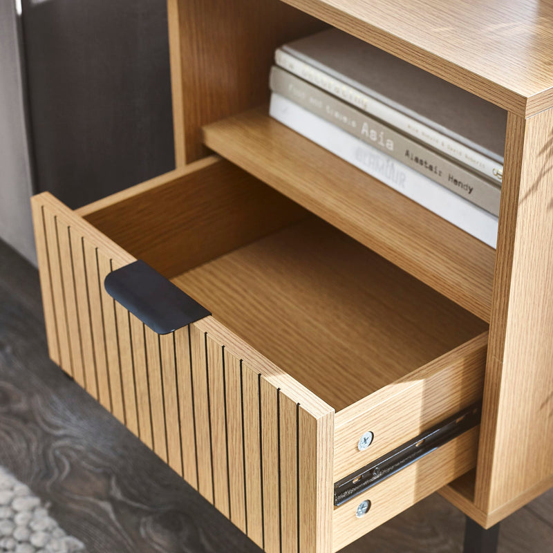 Wooden shelf with a drawer and books on a dark floor