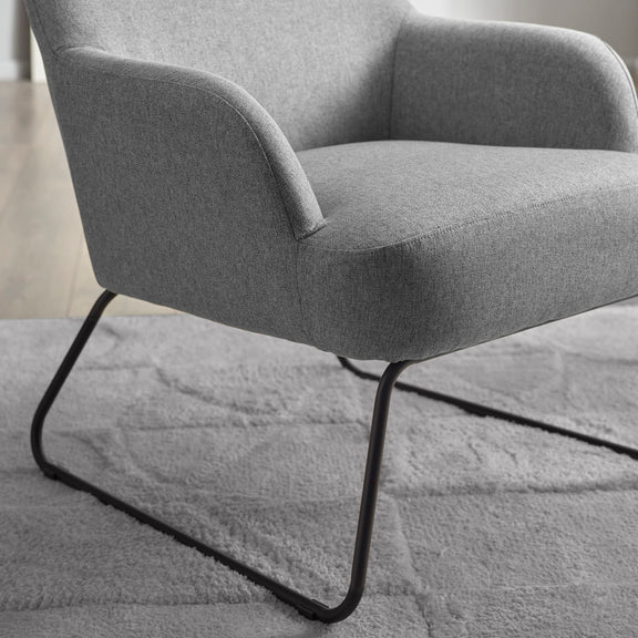Gray armchair with black metal legs on a textured gray surface