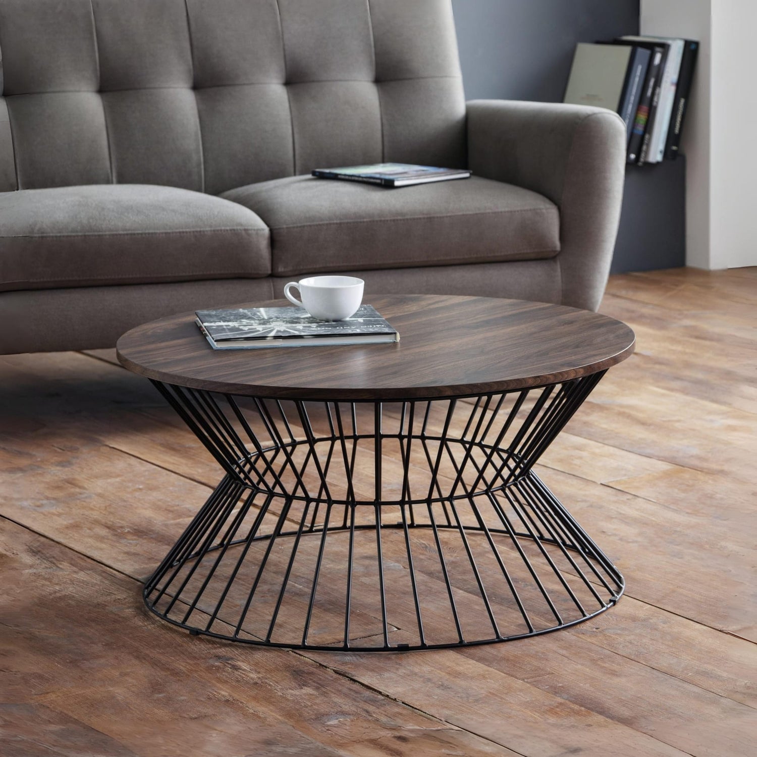 Round wooden coffee table with metal base in a living room setting