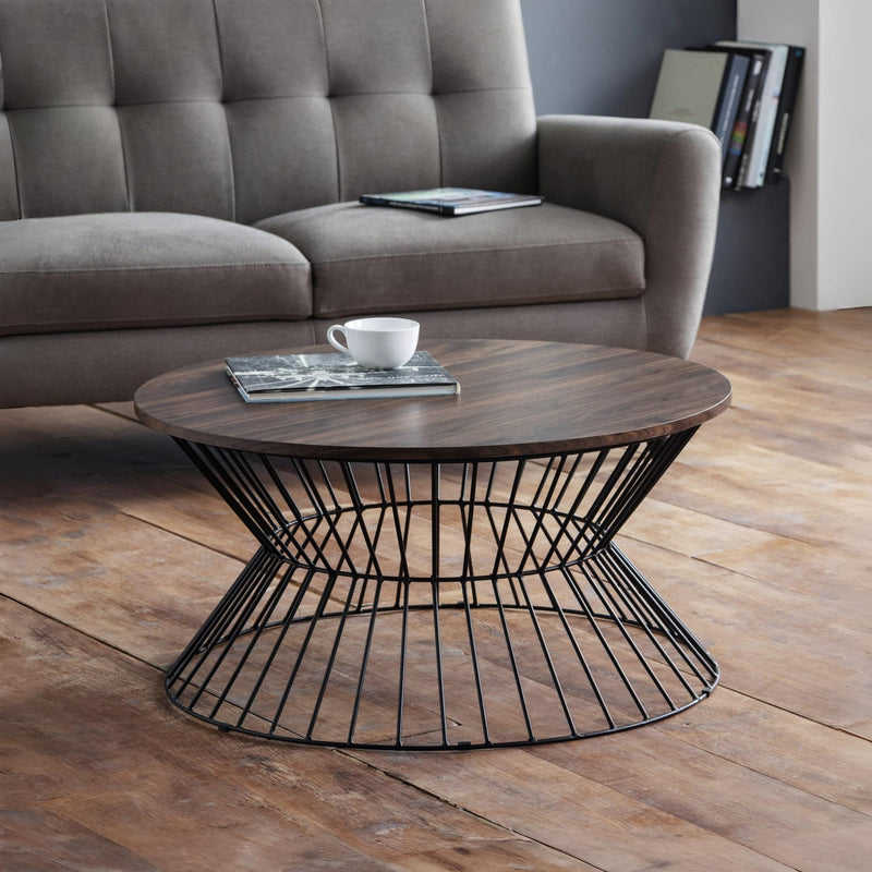 Round wooden coffee table with metal base in a living room setting