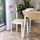 Wooden dining table with a chair in a room with a window and plants.
