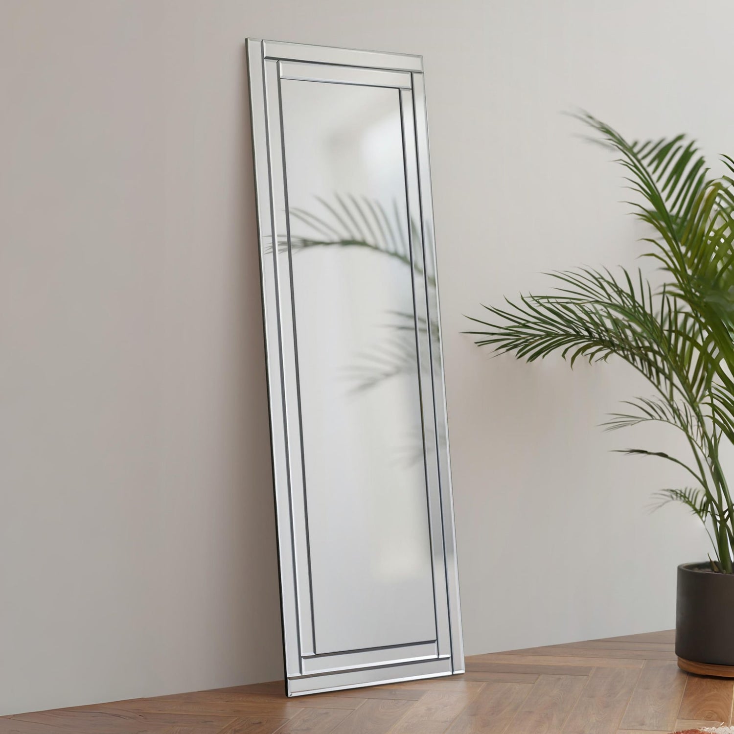 Full length floor mirror with silver frame leaning against wall