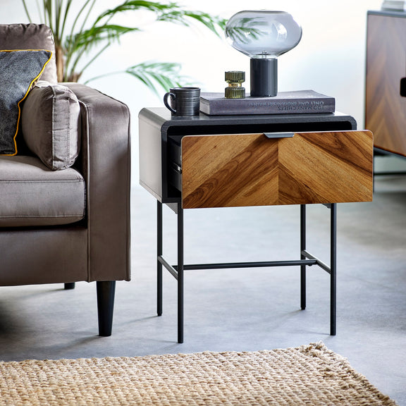 Modern side table with wooden finish and black metal legs in a living room setting.