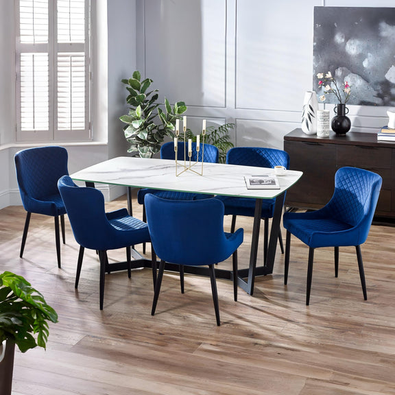 Dining room with a white table and blue chairs on a wooden floor.