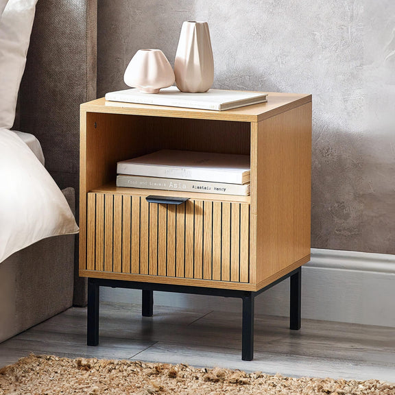 Wooden nightstand with books and a vase in a bedroom setting