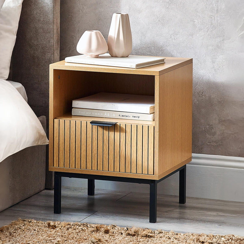 Wooden nightstand with books and a vase in a bedroom setting