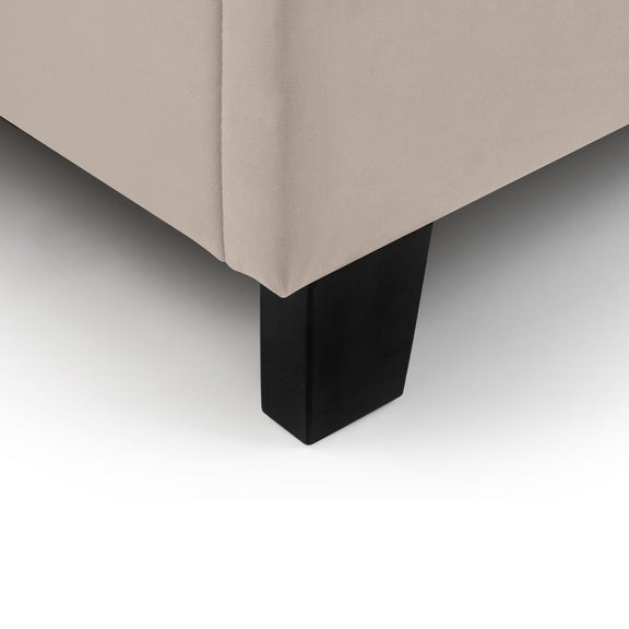 Close-up of a beige upholstered chair with a black metal leg on a light gray background
