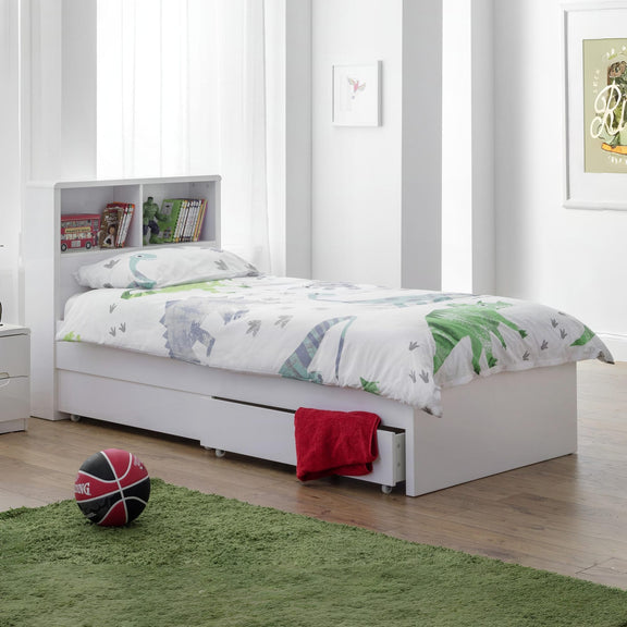 White bed with green bedding in a room with a basketball on the floor.