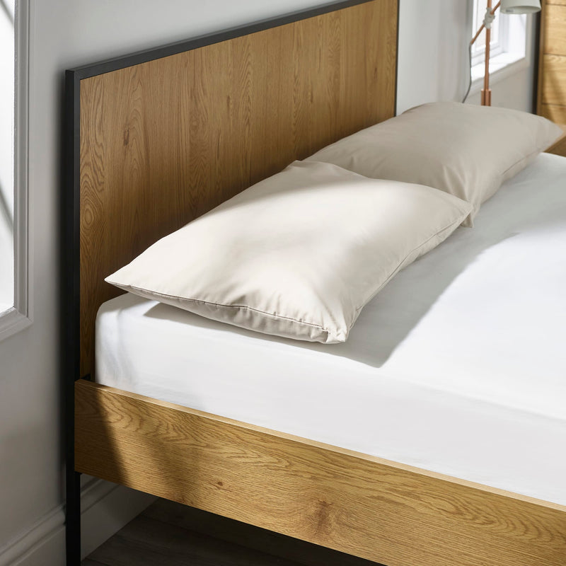 Wooden bed frame with white bedding and pillows in a bedroom setting