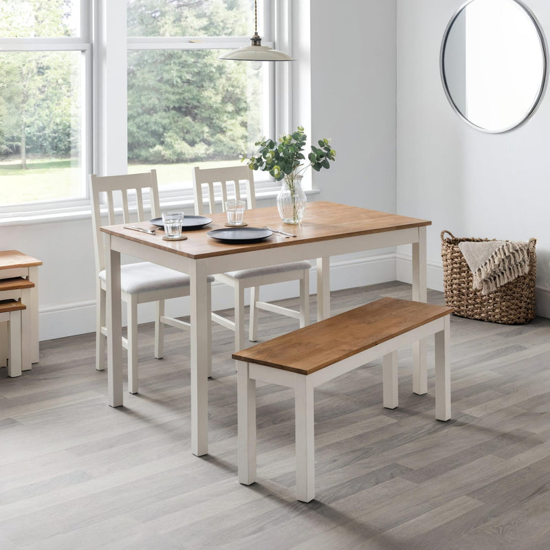 Dining room with wooden table, chairs, and bench in a bright room.