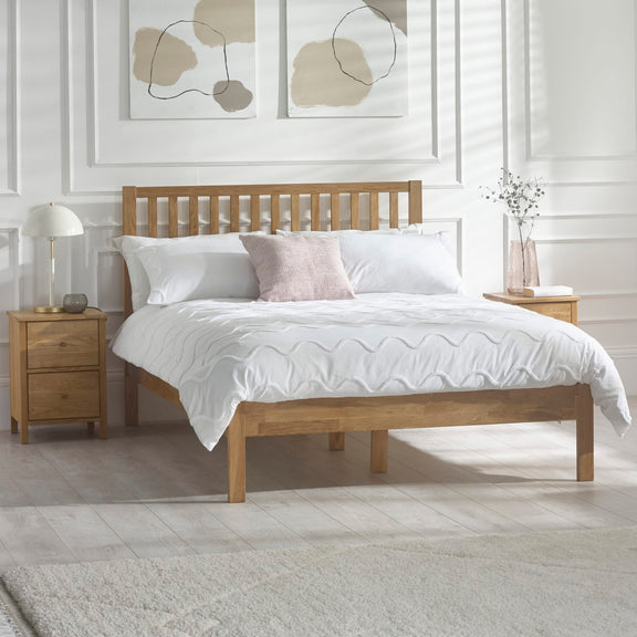 Wooden bed with white bedding in a room with abstract wall art and nightstands.