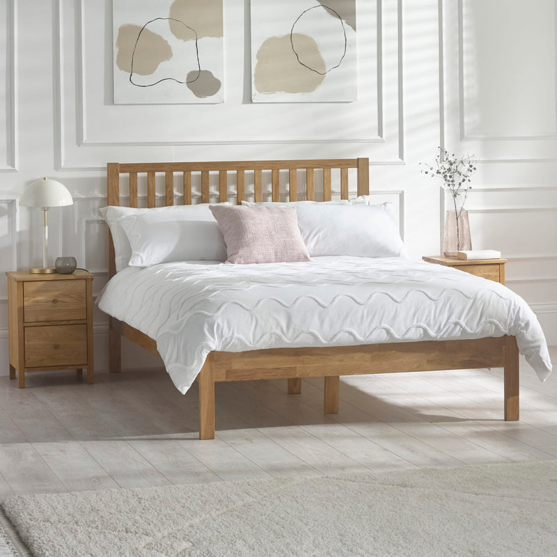 Wooden bed with white bedding in a room with abstract wall art and nightstands.