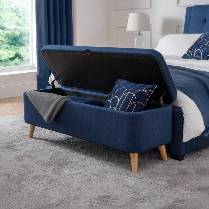 Navy blue storage bench in a room with a bed and window.
