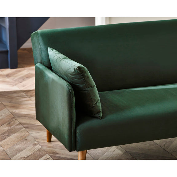 Green sofa with a pillow on a wooden floor