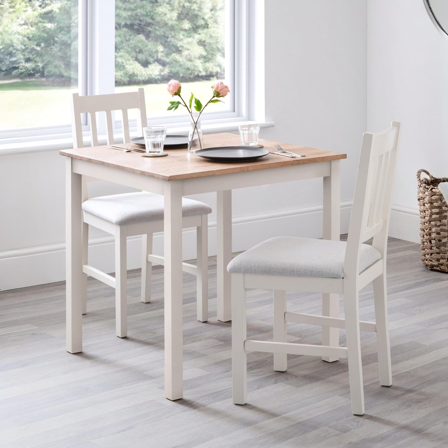 Dining table set with chairs in a room with large windows.