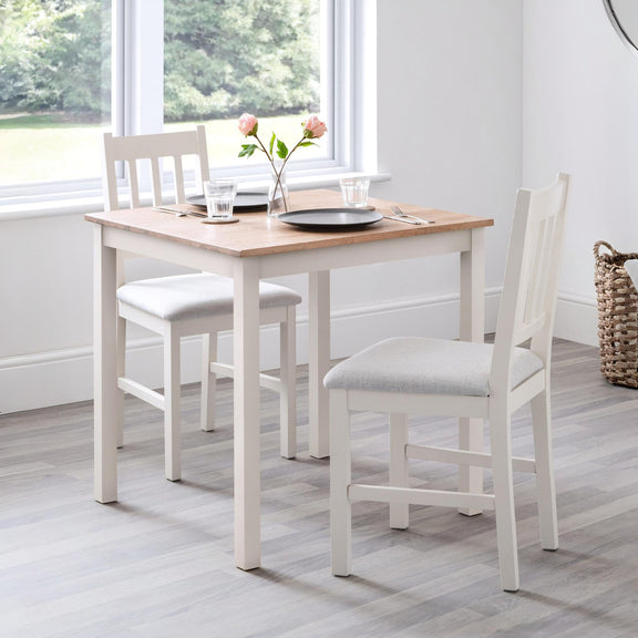 Dining table set with chairs in a room with large windows.