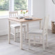 Dining table set with chairs in a room with large windows.