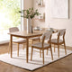 Dining room with wooden table and chairs on a white rug, natural light coming through windows.