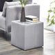 Gray upholstered side table with a vase and books next to a gray sofa.