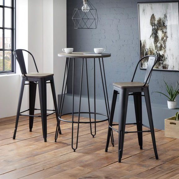 Two black metal bar stools with wooden seats in a room with a high table and decor.