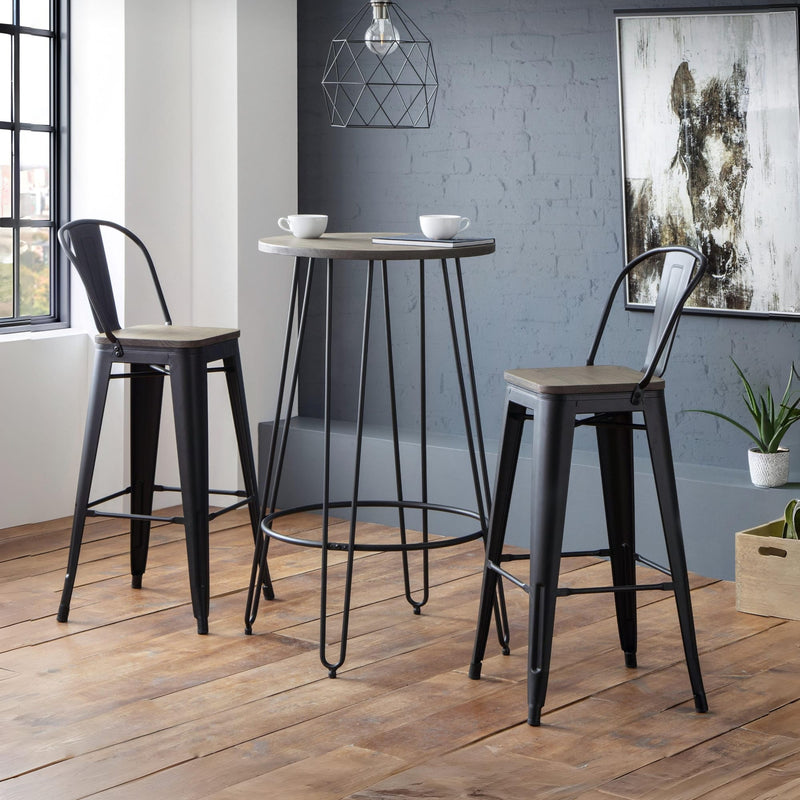 Two black metal bar stools with wooden seats in a room with a high table and decor.