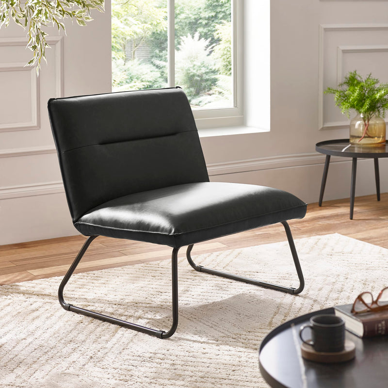 Black leather chair in a modern living room with a window and decor.