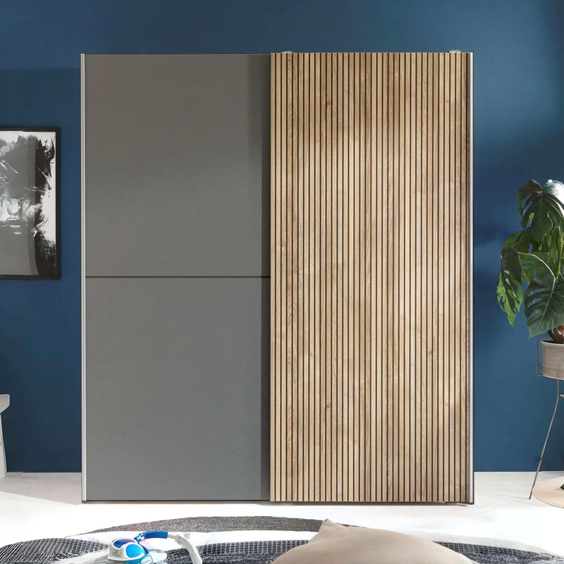 Modern wardrobe with gray and wooden doors against a blue wall.