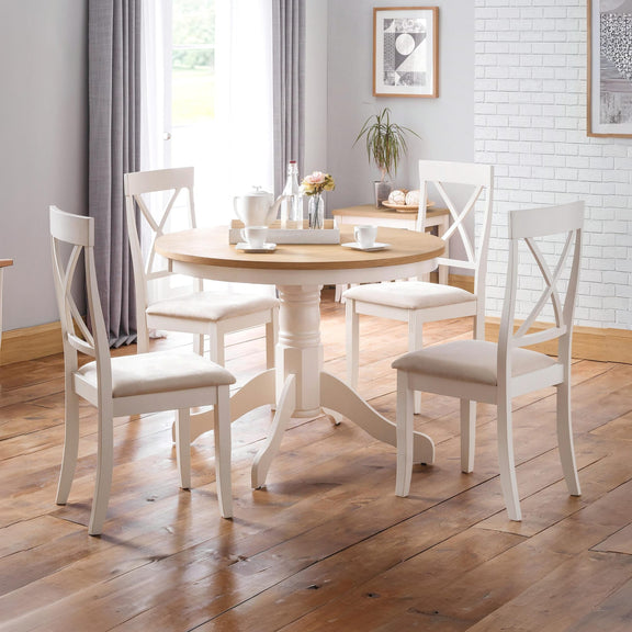 Dining room with round wooden table and white chairs on a wooden floor.
