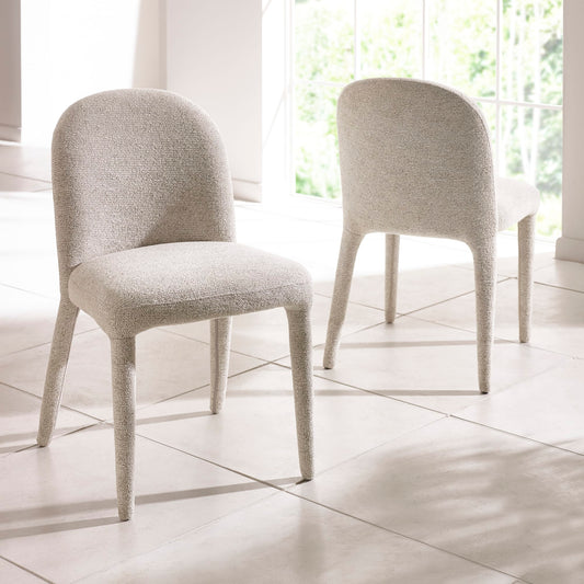 Two gray upholstered chairs on a tiled floor with large windows in the background.