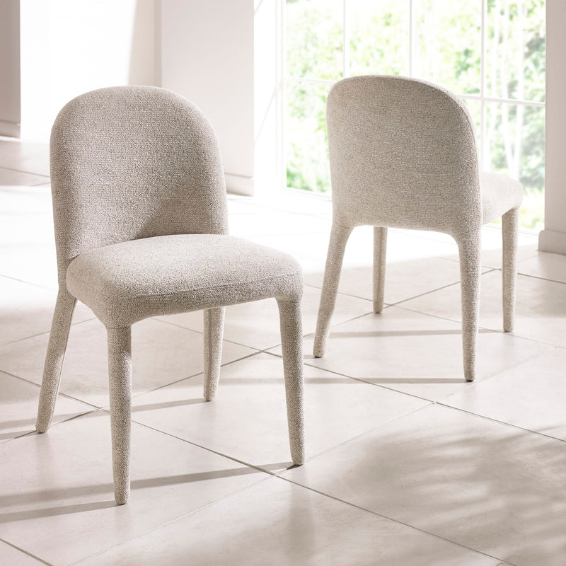 Two gray upholstered chairs on a tiled floor with large windows in the background.