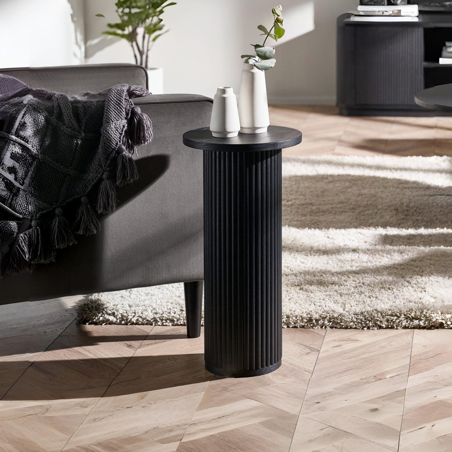 Black side table with decorative items in a living room setting