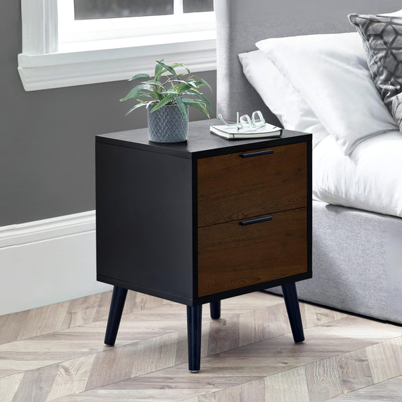 Black and wooden nightstand with a plant and books in a bedroom setting