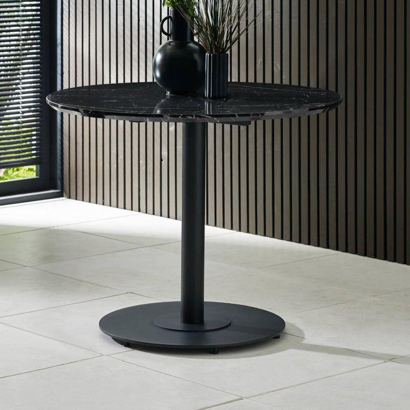 Black marble table with two black vases on a tiled floor.