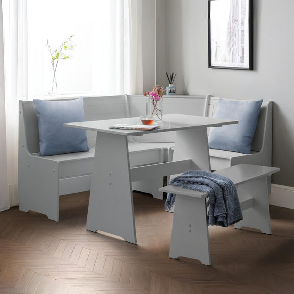 White dining set with bench and table in a room with light gray walls and wooden flooring.
