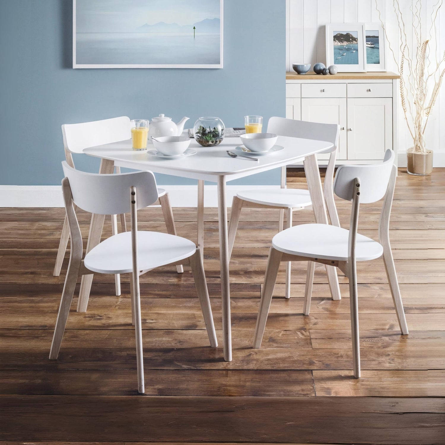 Dining area with a round table and chairs in a room with wooden flooring and blue walls.
