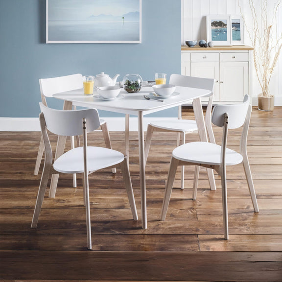 Dining area with a round table and chairs in a room with wooden flooring and blue walls.